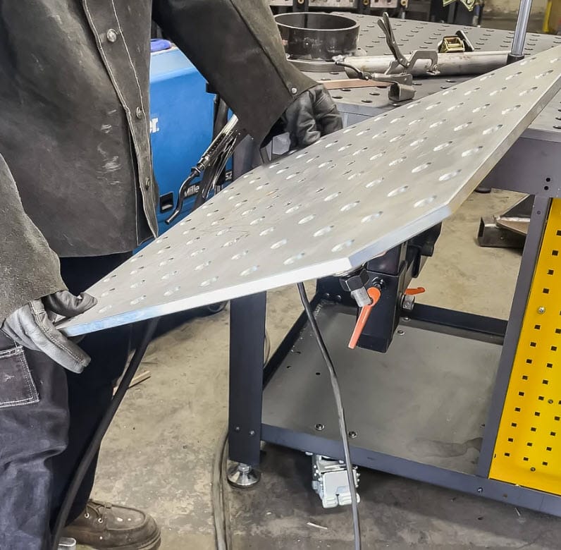 Worker in protective gear adjusting a BuildPro welding table top