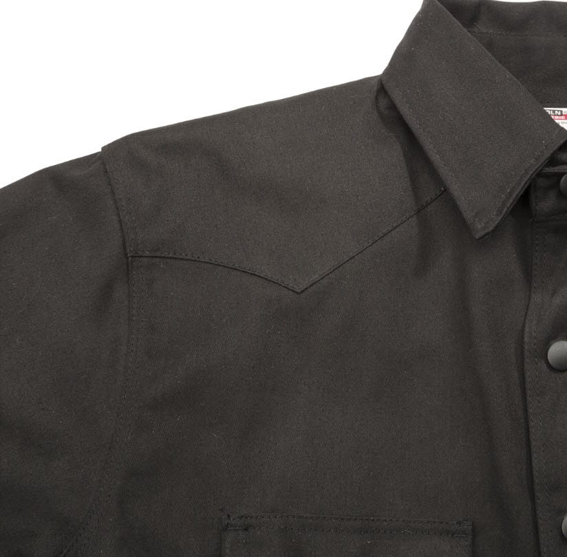 Close up of black western style shirt with pointed shoulder yoke and snap buttons