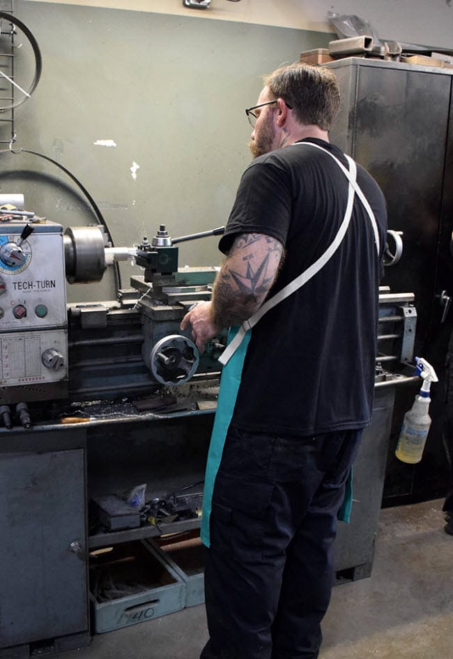 Worker wearing a Tillman apron operating a metal lathe