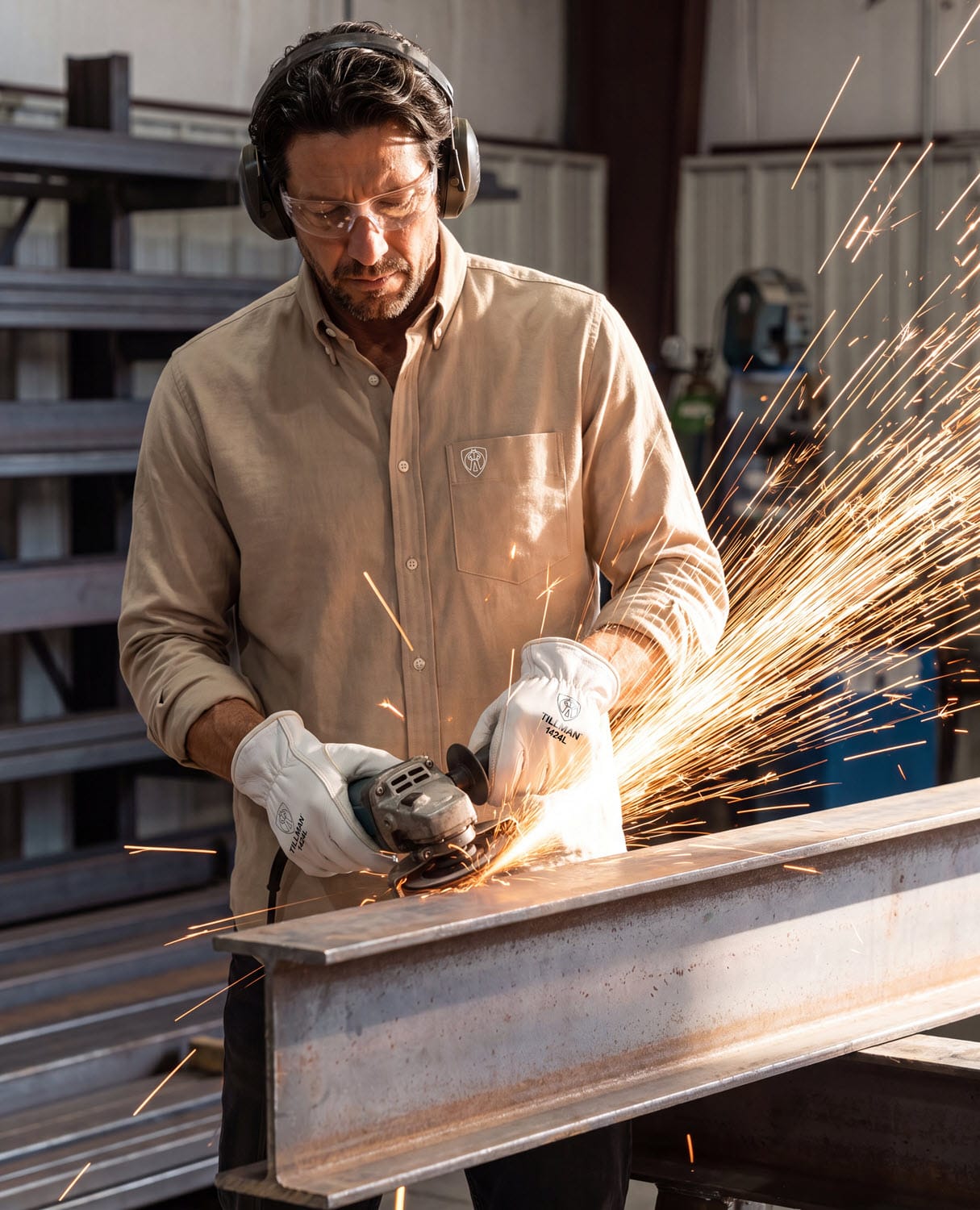 Worker wearing Tillman 1424L gloves using an angle grinder on a steel beam