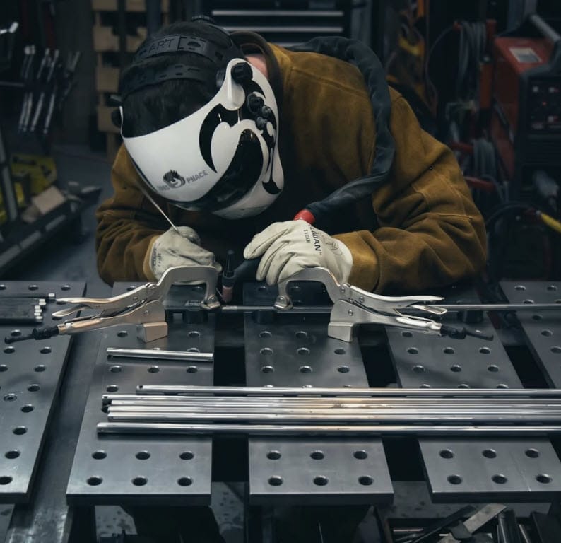 Welder using BuildPro welding table and clamps to join metal rods