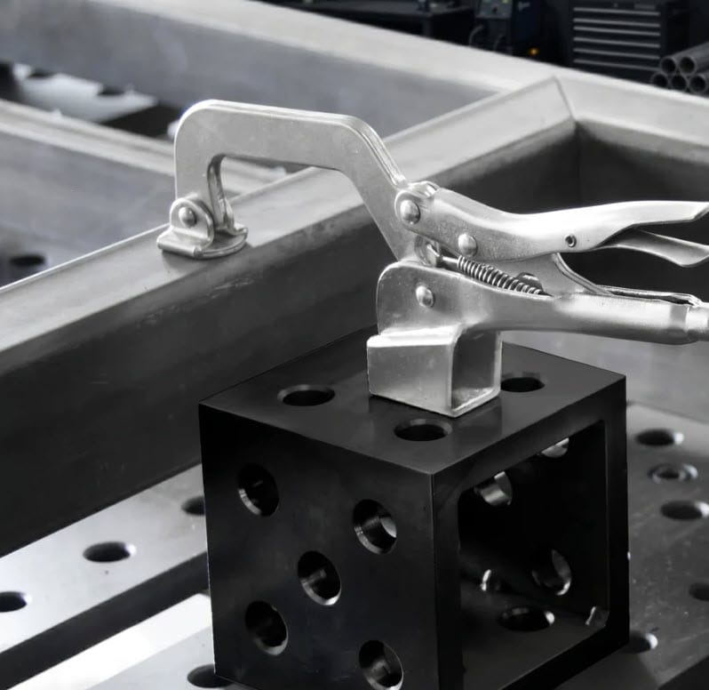 BuildPro locking clamp securing metal square block to welding table