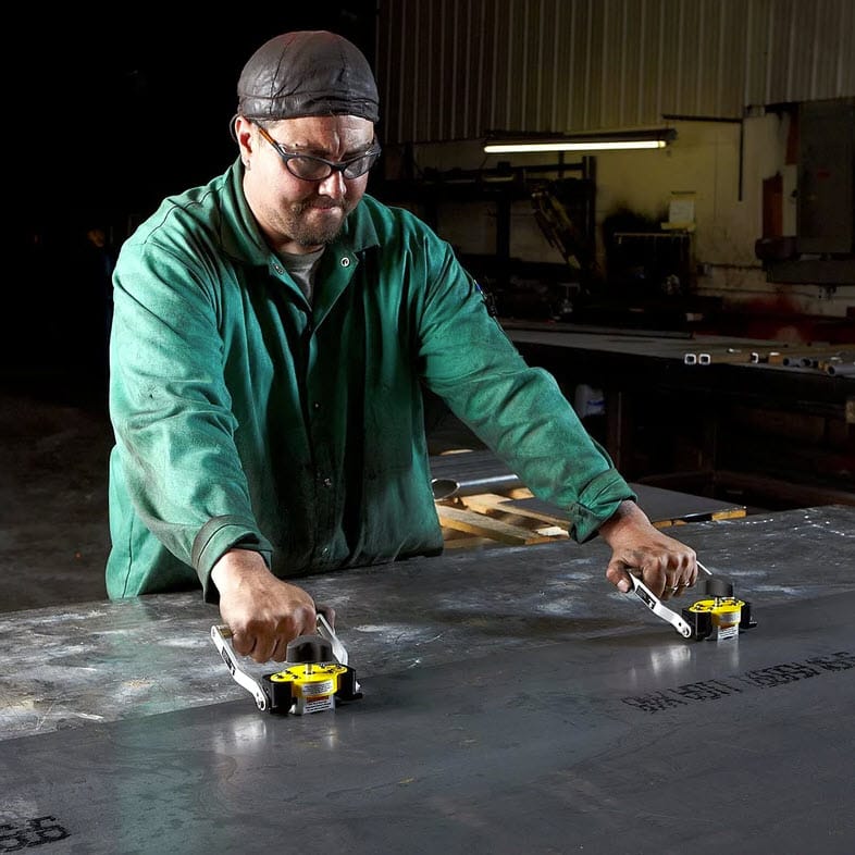Worker using two Magswitch magnetic lifters to move a large steel sheet